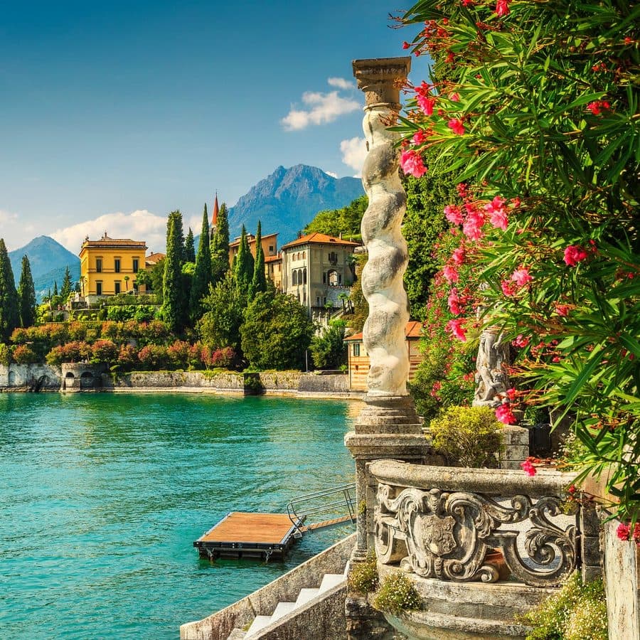 A lakeside villa garden with flowering oleander and mountains beyond